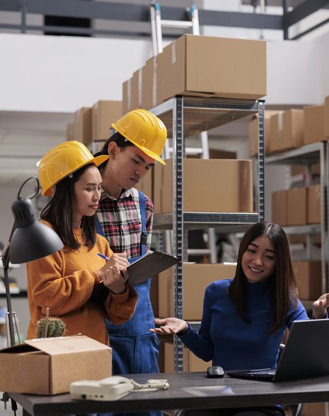 Storehouse employees getting inventory instruction from operator and taking notes. Shipment manager explaining logistics and distribution supply chain to industrial warehouse workers